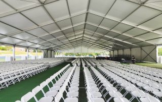 tables and chairs under a large clear span structure for a college graduation